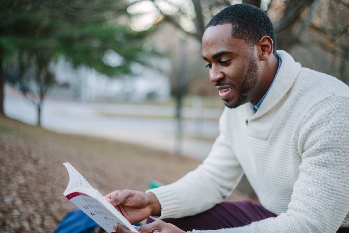 A man reading a book while sitting outside.