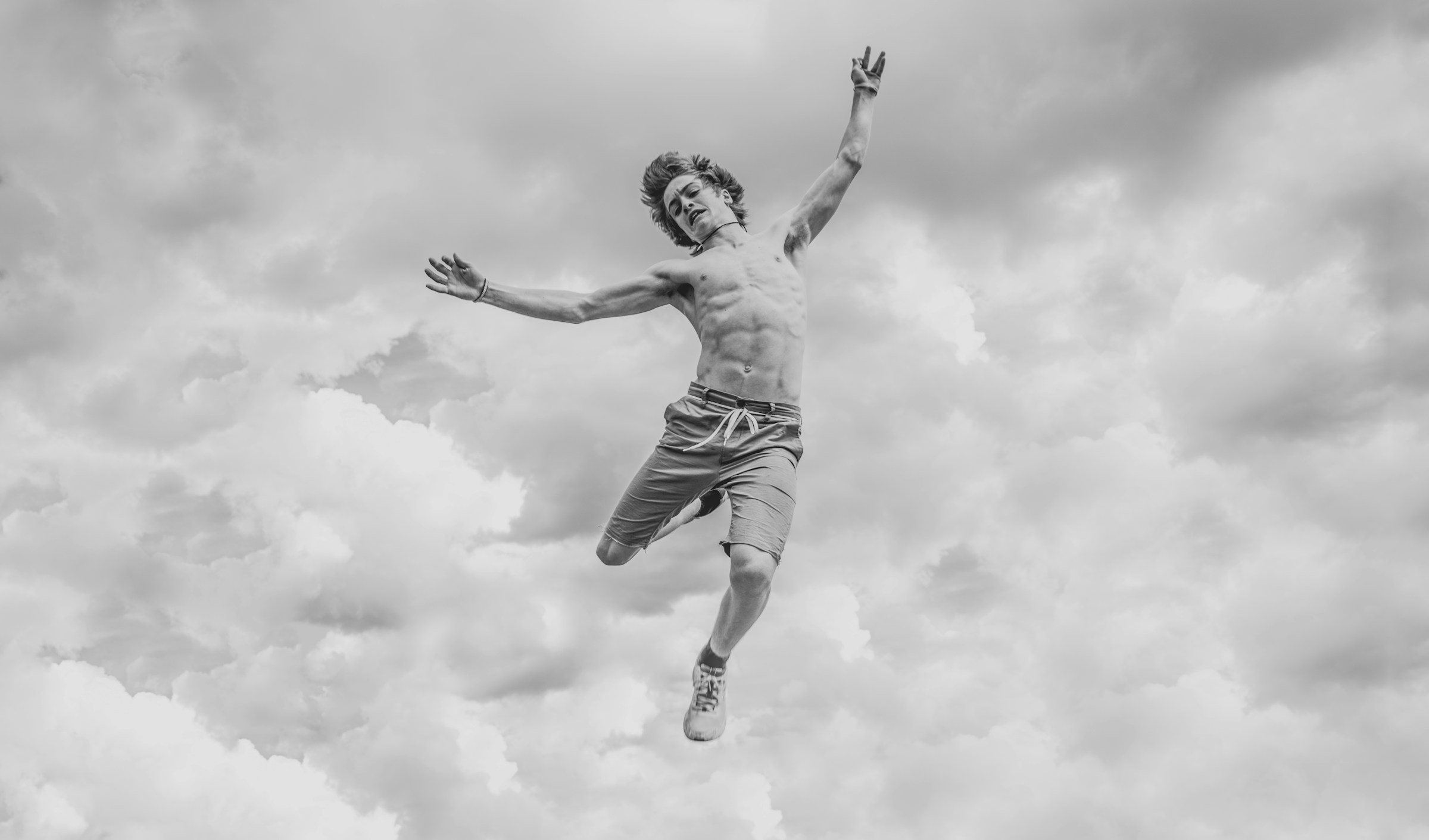 Shirtless man jumping high in the air in black and white